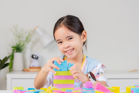 little girl wearing a bright shirt is happy Playing colorful block puzzles. in the white roomの写真素材