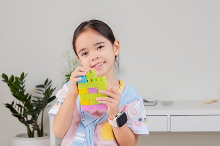 little girl wearing a bright shirt is happy Playing colorful block puzzles. in the white roomの写真素材