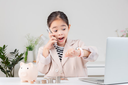 little girl wearing a cream suit analyzing coins concept of finance and investment in white roomの写真素材