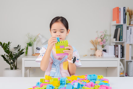little girl wearing a bright shirt is happy Playing colorful block puzzles. in the white roomの写真素材