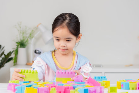 little girl wearing a bright shirt is happy Playing colorful block puzzles. in the white roomの写真素材