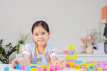 little girl wearing a bright shirt is happy Playing colorful block puzzles. in the white roomの写真素材