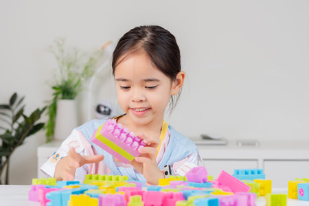 little girl wearing a bright shirt is happy Playing colorful block puzzles. in the white roomの写真素材