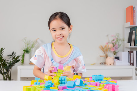 little girl wearing a bright shirt is happy Playing colorful block puzzles. in the white roomの写真素材