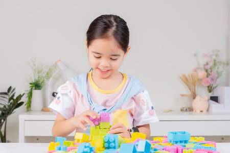 little girl wearing a bright shirt is happy Playing colorful block puzzles. in the white roomの写真素材