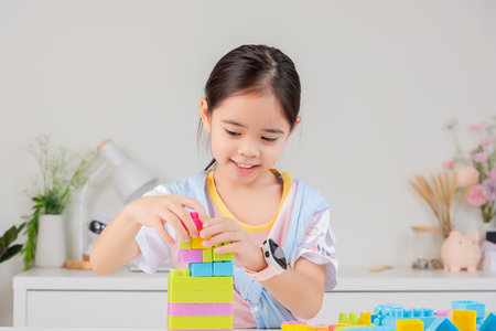little girl wearing a bright shirt is happy Playing colorful block puzzles. in the white roomの写真素材