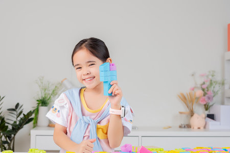 little girl wearing a bright shirt is happy Playing colorful block puzzles. in the white roomの写真素材
