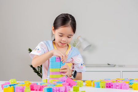 little girl wearing a bright shirt is happy Playing colorful block puzzles. in the white roomの写真素材