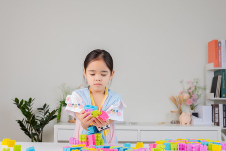 little girl wearing a bright shirt is happy Playing colorful block puzzles. in the white roomの写真素材
