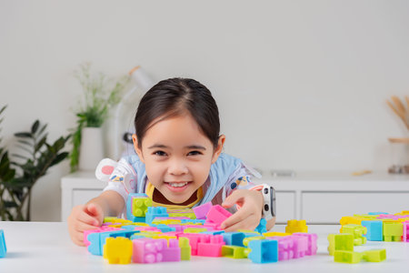 little girl wearing a bright shirt is happy Playing colorful block puzzles. in the white roomの写真素材
