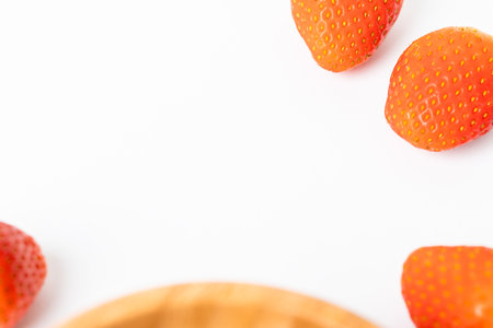 A close up of a bowl of strawberries with a white background. The bowl is filled with strawberries and the strawberries are arranged in a way that they are almost touching each otherの写真素材