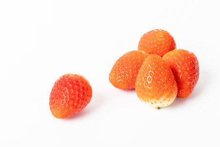 A bunch of strawberries are sitting on a white background. The strawberries are all different sizes and are arranged in a way that they are not touching each otherの写真素材