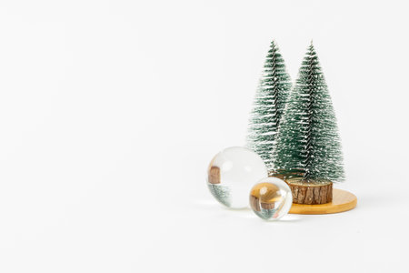 A Christmas tree with two small trees and a glass ball in the middle. The scene is set on a white backgroundの写真素材