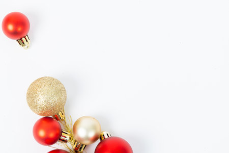 A bunch of red and gold Christmas ornaments are scattered on a white background. The scene conveys a festive and joyful mood, as the bright colors of the ornamentsの写真素材