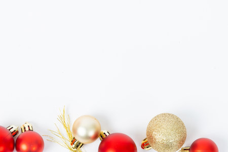 A row of red and gold ornaments on a white background. The gold ornaments are larger than the red onesの写真素材