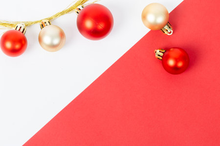 A red and gold ornamented string of Christmas ornaments is hanging from a red background. The red background is a contrasting color to the gold and red ornaments, creating a festive and joyful moodの写真素材