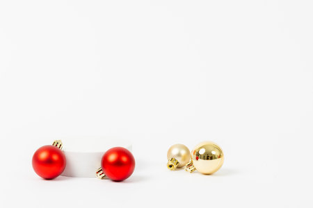 Three Christmas ornaments, one red and two gold, are displayed on a white background. The red ornament is the largest and is positioned in the center, while the two gold ornaments are smallerの写真素材