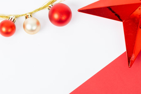 A red star sits on a red background with three red and gold Christmas ornaments. The star is surrounded by a white backgroundの写真素材
