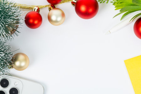 A Christmas tree with red and gold ornaments and a pen on a white background. The pen is on a yellow piece of paperの写真素材