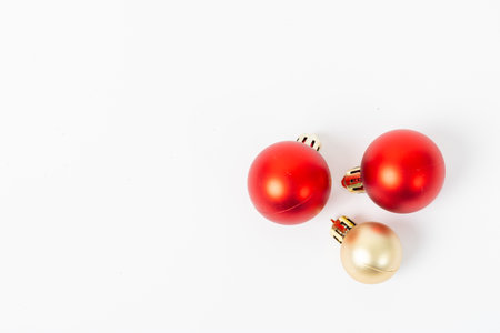 Three red and gold ornaments are sitting on a white background. The red ornaments are larger than the gold onesの写真素材