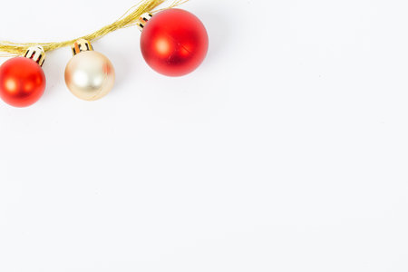 Three red and gold Christmas ornaments hanging from a string. The gold ornaments are larger than the red onesの写真素材
