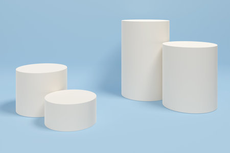 Four white cylinders arranged in a row on a blue background. The cylinders are of varying sizes and are placed in a way that creates a sense of depth and dimension. Scene is one of simplicityの写真素材