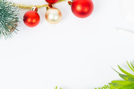 A white background with a bunch of red and gold Christmas ornaments. The red and gold ornaments are hanging from a tree branchの写真素材