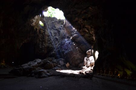 Buddha statue and Natural light inside the cave at Khaoluang, Phetchaburi Province, Thailand.の写真素材