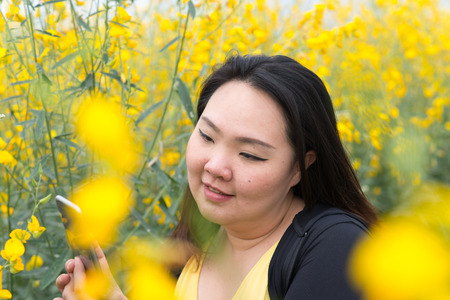 Happy Asian fat woman take photo by her self in flower garden
