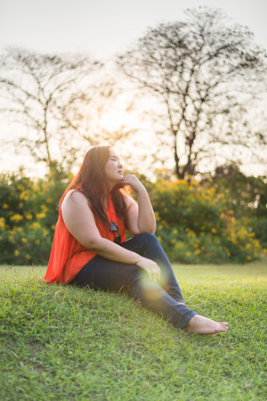 Beautiful fat woman relax fashion in the green park with lens flareの写真素材