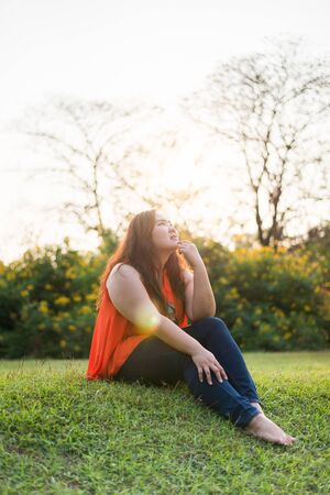 Beautiful fat woman relax fashion in the green park with lens flareの写真素材