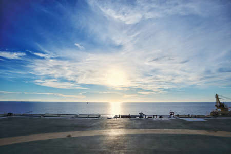 Offshore platform helideck with sunset background.
