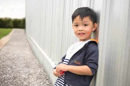 Happy cute boy leaning wall of building and perspective way background