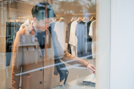 Young man shopping in the clothes shop. Looking through the windowの写真素材