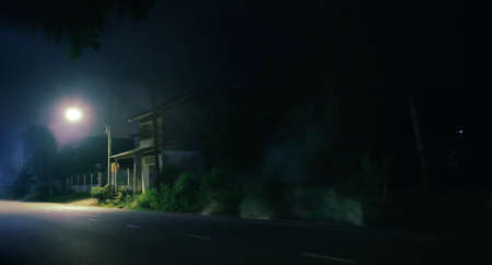 Old wooden house and smoke at night . Horror scene