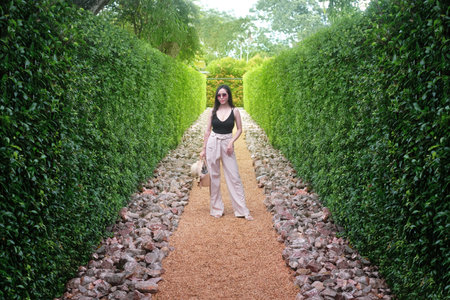 Young woman standing in green bushes labyrinth , hedge mazeの写真素材
