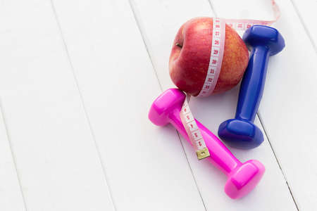 Colorful dumbbell, apple and measuring tape in vintage tone, time to exercise work out concept