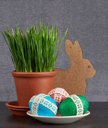 easter eggs in saucer and green wheat in the clay pot  on gray backgroundの写真素材