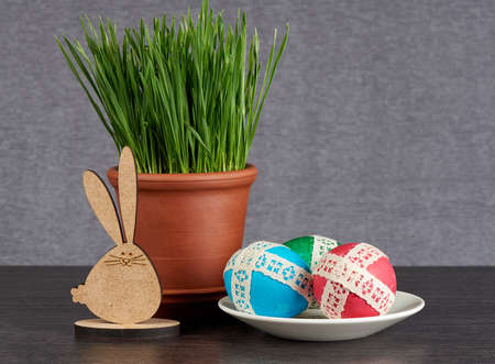 easter eggs in saucer and green wheat in the clay pot  on gray backgroundの写真素材