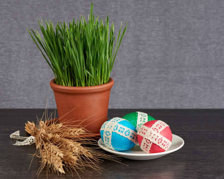 easter eggs in saucer and green wheat in the clay pot  on gray backgroundの写真素材