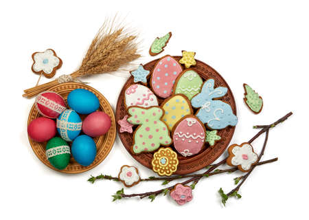 easter eggs and easter gingerbread in wooden plates on white backgroundの写真素材
