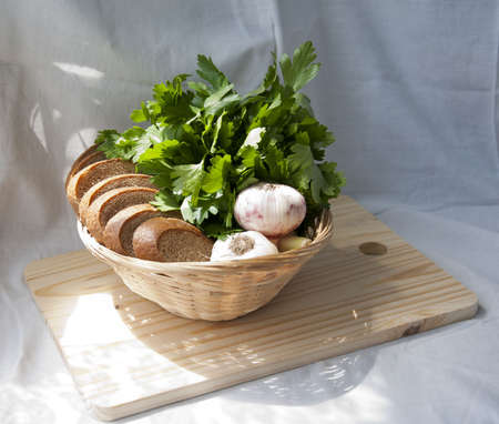 Rye bread slice with garlic and herbs (parsley) in a basket on chopping boardの写真素材
