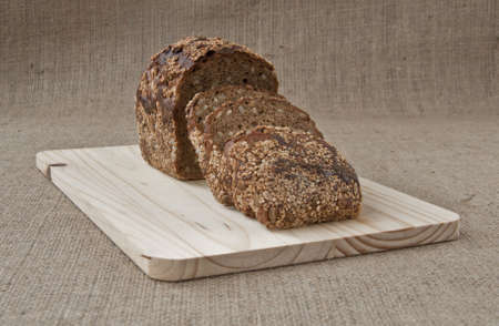 on the kitchen blackboard is sliced rye bread with grains on the background of coarse cloth