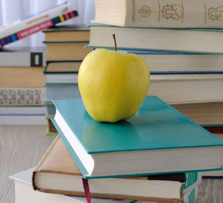 Apple on stack of books on the table among the other booksの写真素材