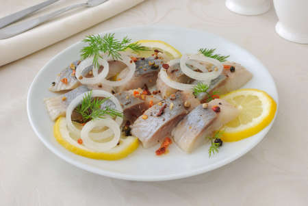Slices of salted herring fillet with onion, lemon and spicesの写真素材