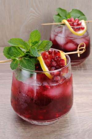 Pomegranate cocktail with slices of lime, mint and iceの写真素材