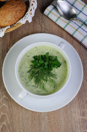 A bowl of soup with dill sauce and parsley on the table with croutonsの写真素材