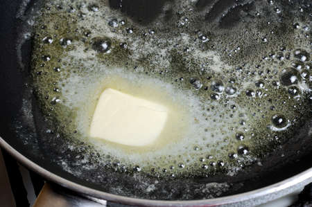 Piece of butter melting on   frying pan. Step by step recipeの写真素材