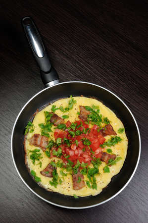 Omelet bacon slices, tomatoes with herbs in a panの写真素材