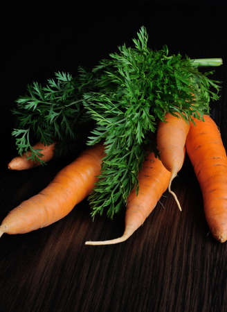 bundle of raw carrots on the table dark backgroundの写真素材